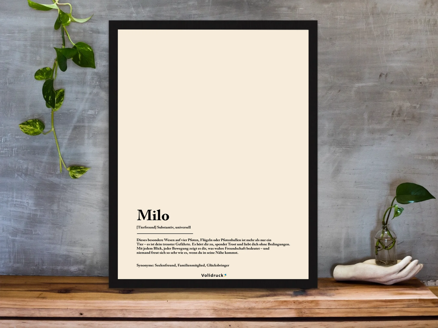 framed-art-print-standing-on-a-wooden-desk-against-a-concrete-wall-near-a-hand-decoration-a10403-2