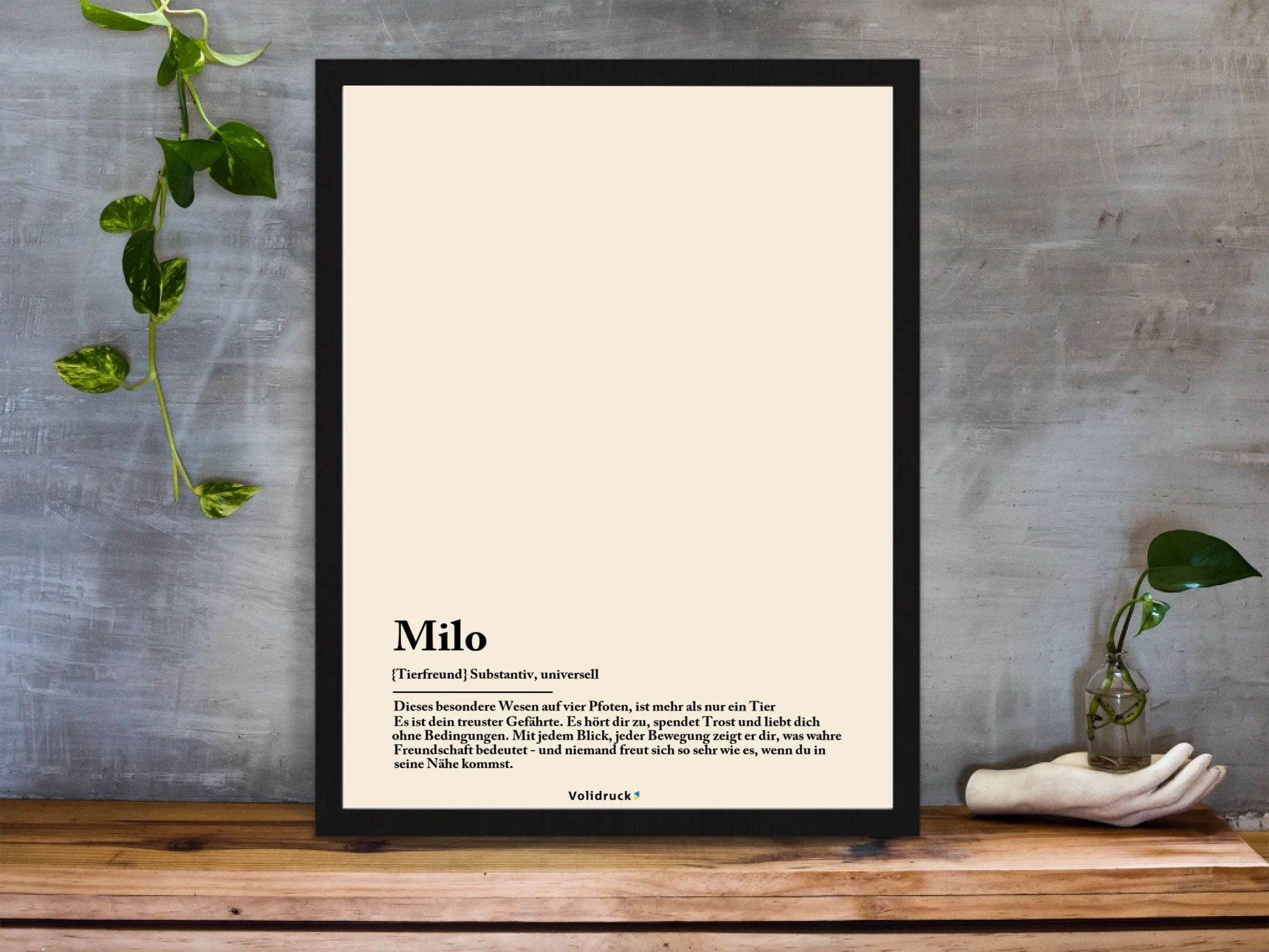 framed-art-print-standing-on-a-wooden-desk-against-a-concrete-wall-near-a-hand-decoration-a10403-2